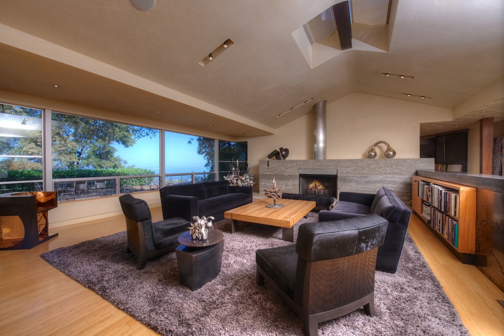This is an example of a contemporary open concept living room in San Francisco with beige walls, light hardwood floors, a standard fireplace and no tv.