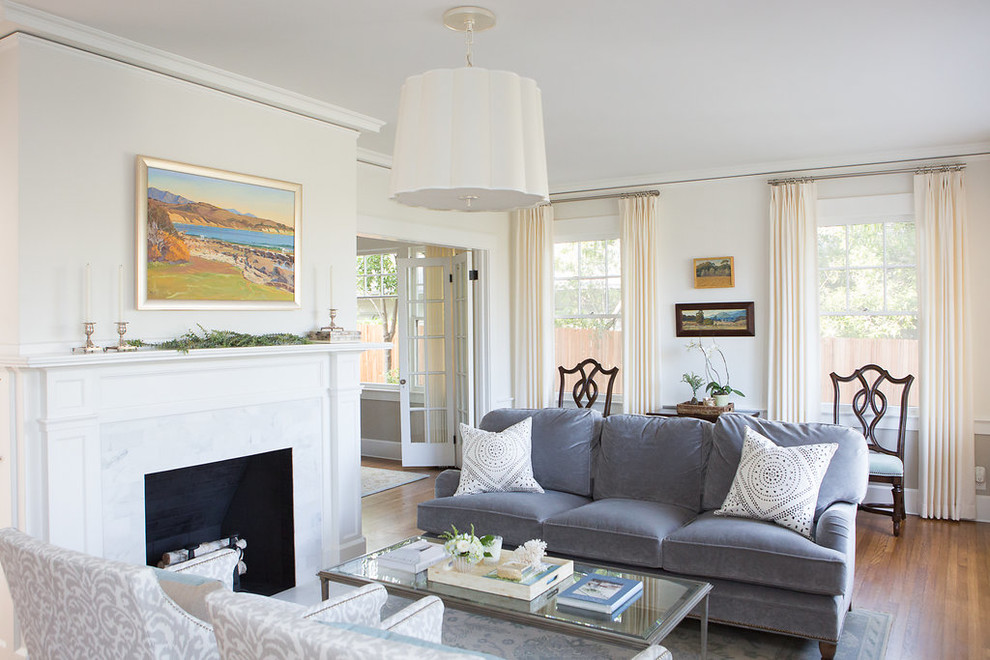 Inspiration for a mid-sized beach style formal open concept living room in Santa Barbara with beige walls, medium hardwood floors, a standard fireplace, a plaster fireplace surround, no tv and brown floor.