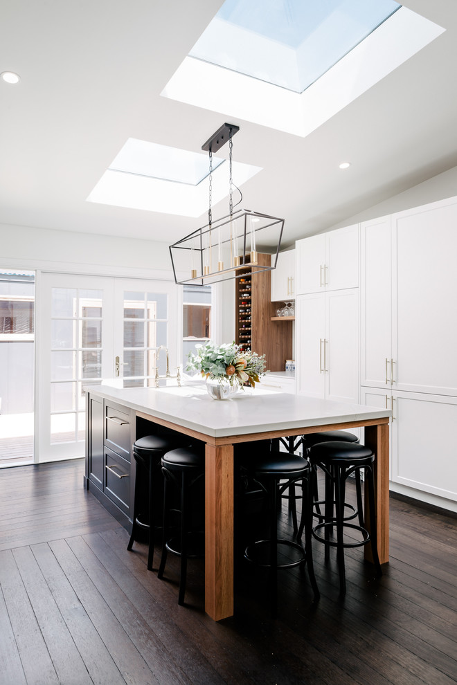 Inspiration for a large transitional galley eat-in kitchen in Hobart with a farmhouse sink, shaker cabinets, white cabinets, quartz benchtops, dark hardwood floors, with island, brown floor, white benchtop and panelled appliances.