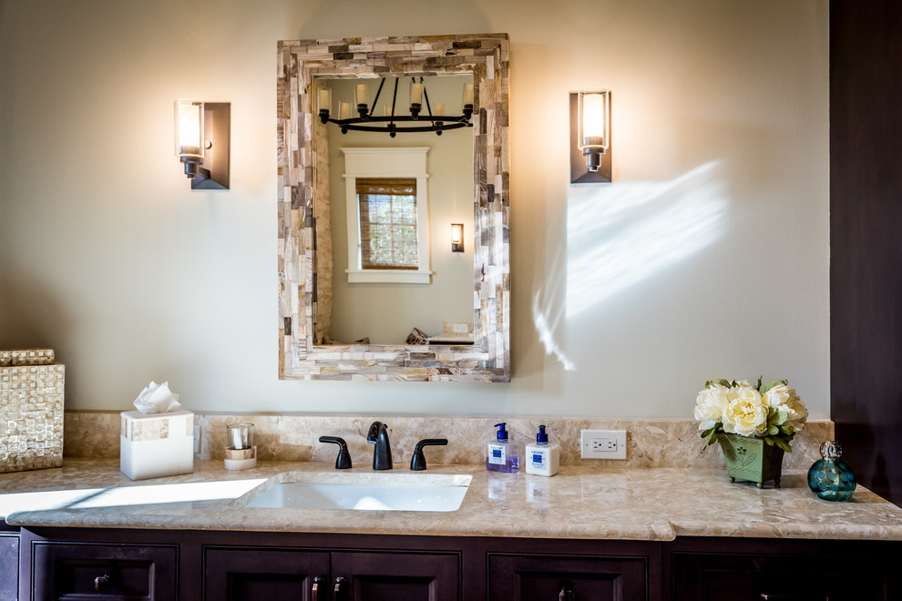 Photo of a large country master bathroom in Charleston with recessed-panel cabinets, dark wood cabinets, a freestanding tub, an open shower, beige tile, travertine, beige walls, travertine floors, an undermount sink, limestone benchtops, beige floor, an open shower and a two-piece toilet.