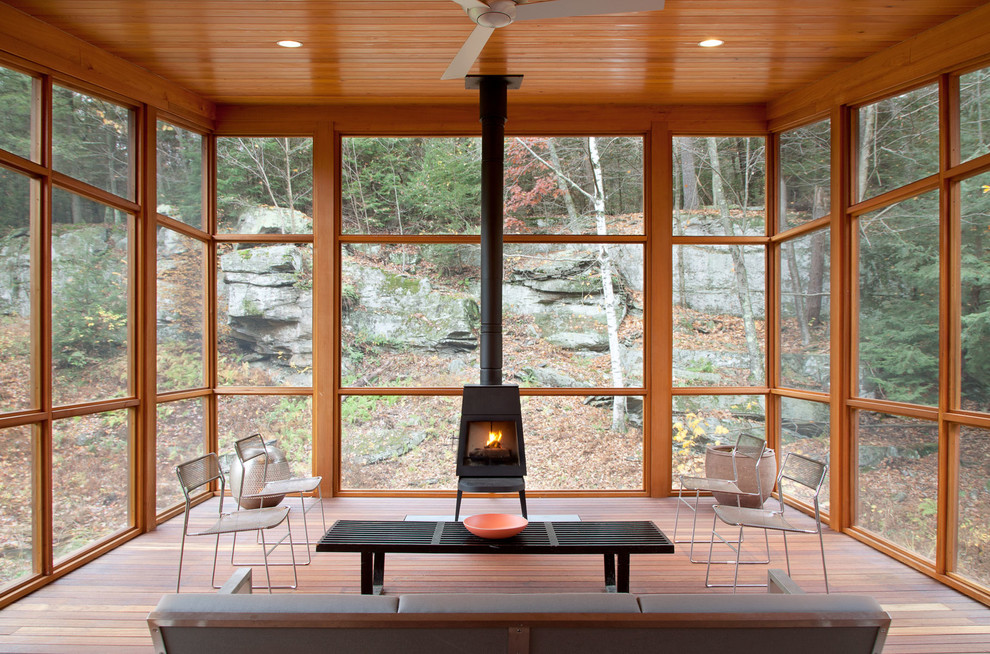 Inspiration for a country sunroom in New York with medium hardwood floors, a wood stove and a standard ceiling.