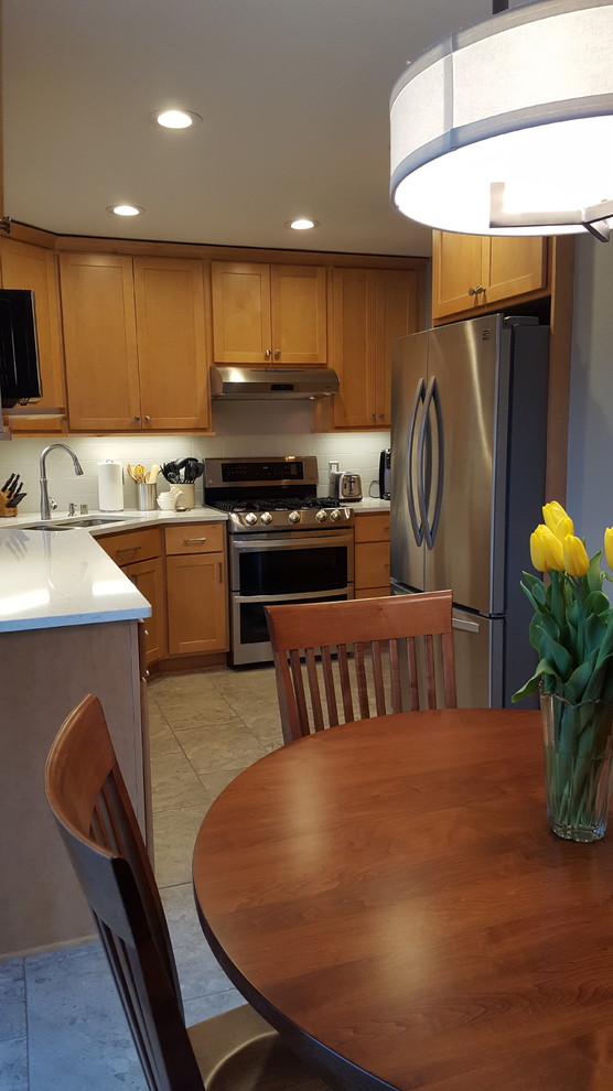 Inspiration for a mid-sized transitional l-shaped ceramic tile eat-in kitchen remodel with an undermount sink, shaker cabinets, light wood cabinets, quartz countertops, gray backsplash, subway tile backsplash, stainless steel appliances and no island