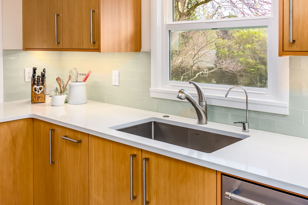 Inspiration for a mid-sized transitional l-shaped eat-in kitchen in Portland with an undermount sink, flat-panel cabinets, light wood cabinets, quartz benchtops, green splashback, ceramic splashback, stainless steel appliances, vinyl floors, no island, beige floor and white benchtop.