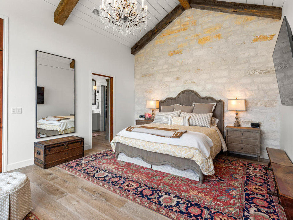 This is an example of a country master bedroom in Austin with white walls, medium hardwood floors and beige floor.