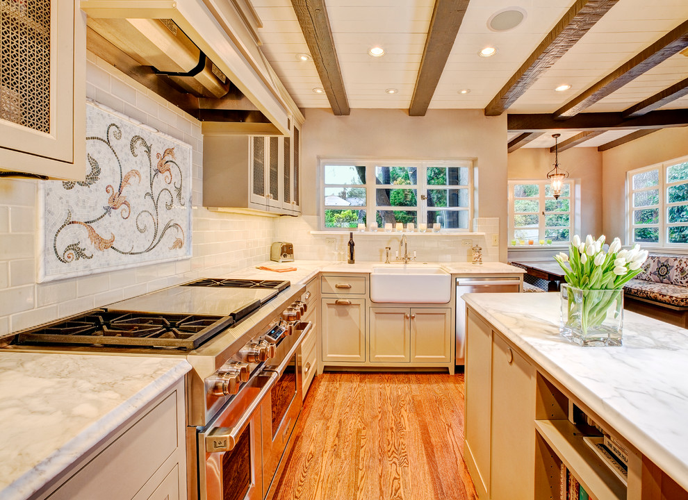 Design ideas for a mediterranean kitchen in Seattle with subway tile splashback, white splashback, marble benchtops, a farmhouse sink, beige cabinets and recessed-panel cabinets.