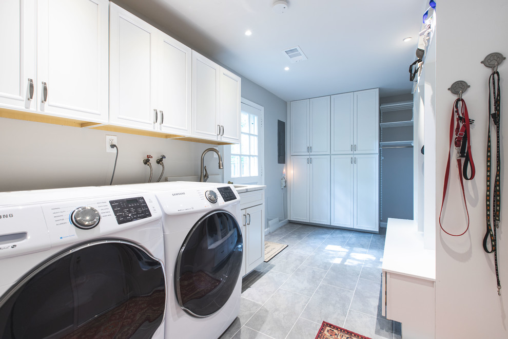 Photo of a large contemporary u-shaped laundry room in DC Metro with an undermount sink, raised-panel cabinets, white cabinets, quartz benchtops, grey splashback, subway tile splashback, vinyl floors, brown floor and white benchtop.