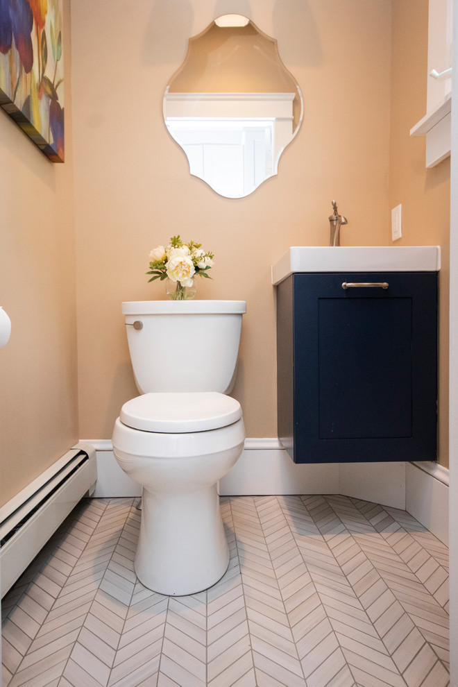 Inspiration for a small modern powder room in Providence with flat-panel cabinets, blue cabinets, a two-piece toilet, beige walls, porcelain floors, a wall-mount sink, grey floor and white benchtops.