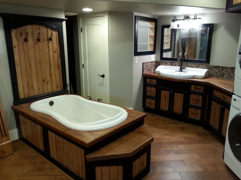 Drop-in bathtub - large rustic master dark wood floor and brown floor drop-in bathtub idea with furniture-like cabinets, dark wood cabinets, gray walls, a drop-in sink and wood countertops