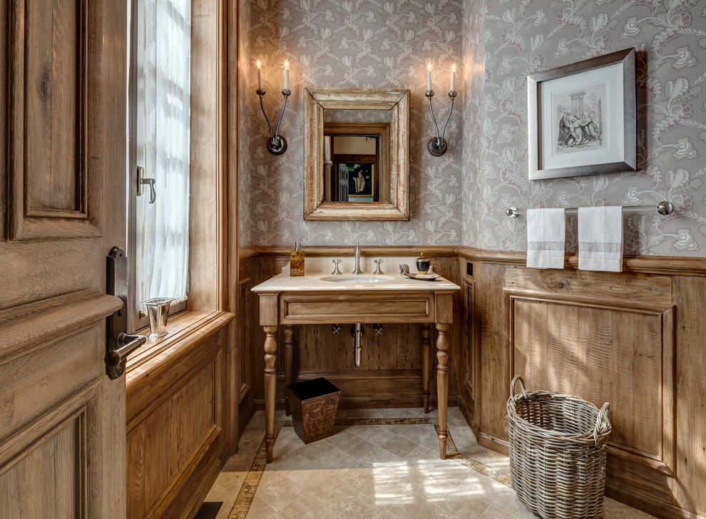 Inspiration for a traditional powder room in New York with medium wood cabinets, limestone floors, an undermount sink, grey walls and beige floor.