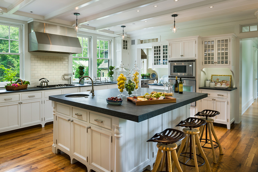 Inspiration for a large traditional l-shaped eat-in kitchen in Philadelphia with stainless steel appliances, an undermount sink, recessed-panel cabinets, white cabinets, soapstone benchtops, white splashback, subway tile splashback, light hardwood floors, with island and brown floor.