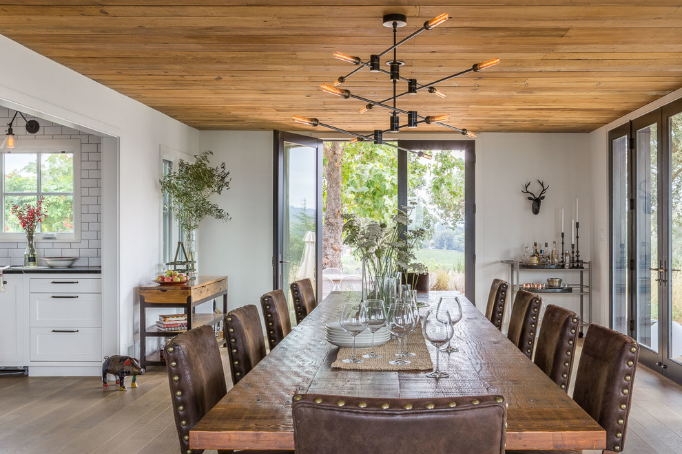 Photo of a country dining room in San Francisco with white walls, light hardwood floors and no fireplace.