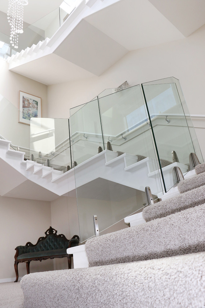 Design ideas for an expansive traditional carpeted u-shaped staircase in Wellington with carpet risers and glass railing.