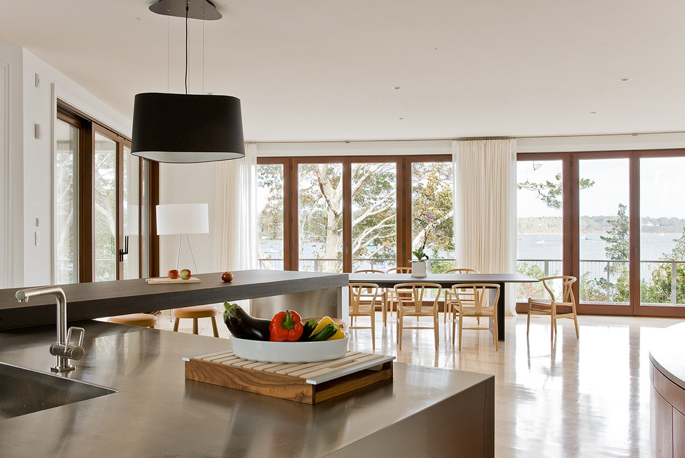 Photo of a contemporary eat-in kitchen in Boston with an integrated sink, stainless steel benchtops, stainless steel appliances, light hardwood floors and a peninsula.