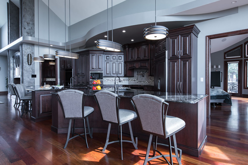 Transitional single-wall medium tone wood floor and brown floor eat-in kitchen photo with an undermount sink, raised-panel cabinets, dark wood cabinets, granite countertops, black appliances, two islands and black countertops