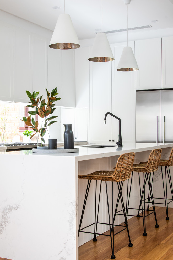 Contemporary eat-in kitchen in Sydney with a double-bowl sink, shaker cabinets, white cabinets, quartz benchtops, window splashback, black appliances, light hardwood floors, multiple islands and multi-coloured benchtop.