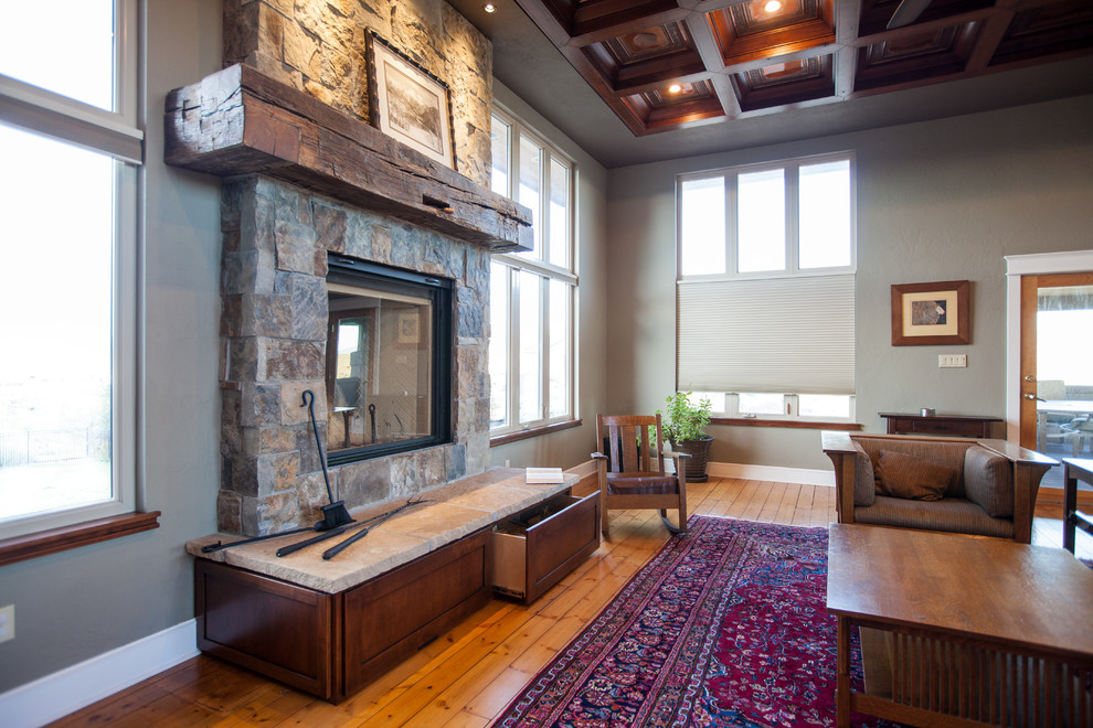 Large arts and crafts enclosed living room in Denver with a library, green walls, medium hardwood floors, a standard fireplace, a stone fireplace surround, a wall-mounted tv and yellow floor.