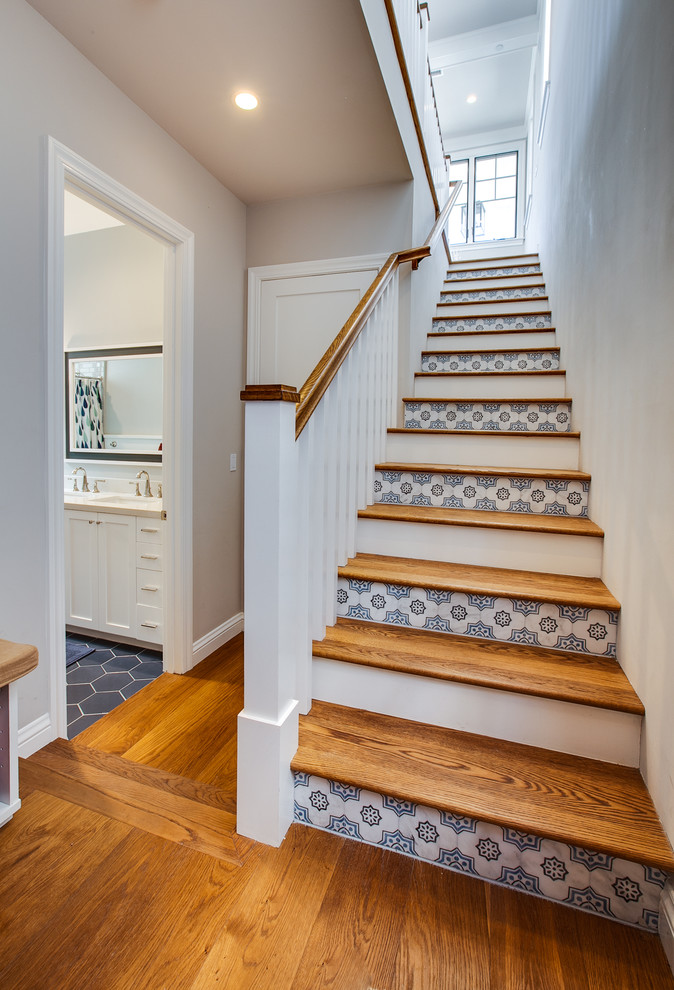 This is an example of a mid-sized beach style wood straight staircase in Los Angeles with tile risers and wood railing.