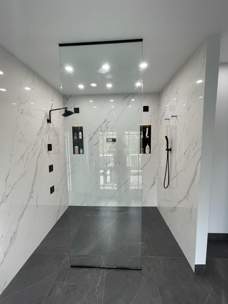 Modern inredning av ett stort svart svart en-suite badrum, med släta luckor, vita skåp, ett fristående badkar, en kantlös dusch, en bidé, vit kakel, porslinskakel, vita väggar, klinkergolv i porslin, ett nedsänkt handfat, bänkskiva i kvartsit, grått golv och med dusch som är öppen