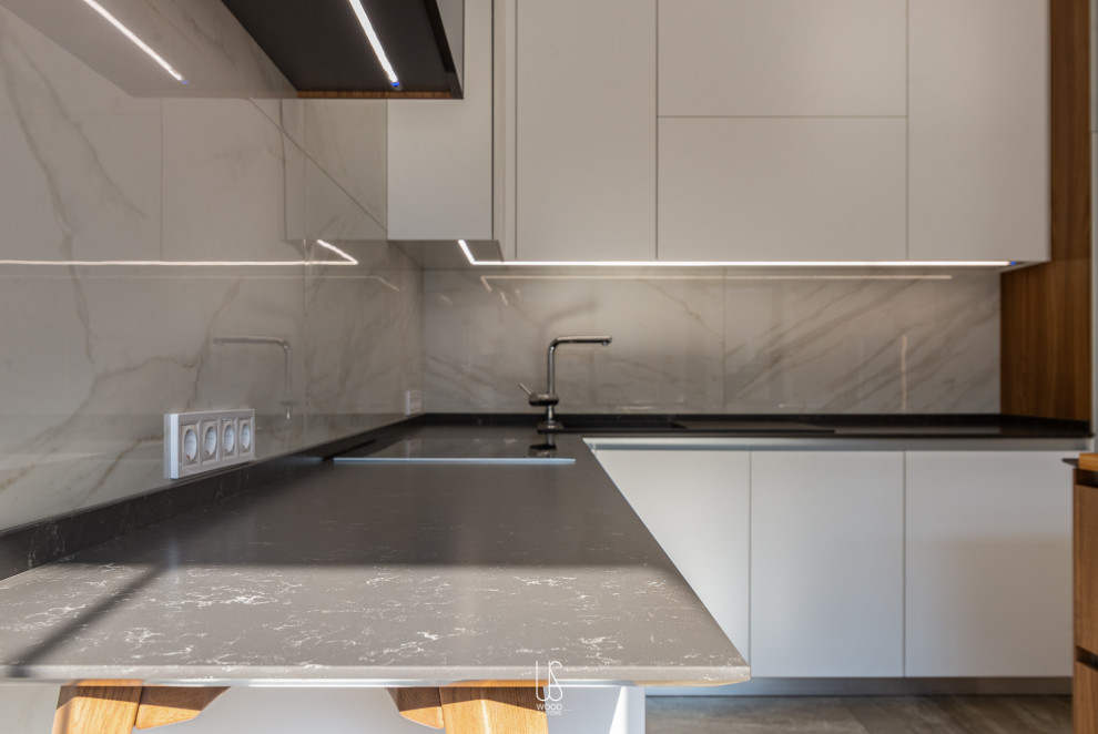 Large modern u-shaped eat-in kitchen in Other with an undermount sink, white cabinets, solid surface benchtops, white splashback, marble splashback, panelled appliances, marble floors, with island, grey floor and black benchtop.