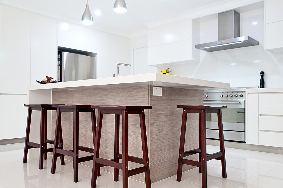 Inspiration for a large contemporary l-shaped open plan kitchen in Brisbane with an undermount sink, flat-panel cabinets, white cabinets, quartz benchtops, white splashback, stone slab splashback, stainless steel appliances, ceramic floors and with island.