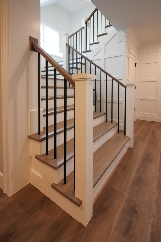 Пример оригинального дизайна: большая п-образная деревянная лестница в стиле неоклассика (современная классика) с деревянными ступенями, деревянными перилами и панелями на стенах