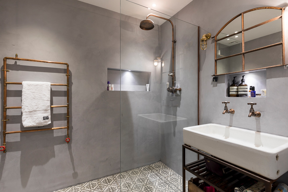 Mid-sized industrial bathroom in London with open cabinets, an open shower, grey walls, cement tiles, grey floor, an open shower and a trough sink.