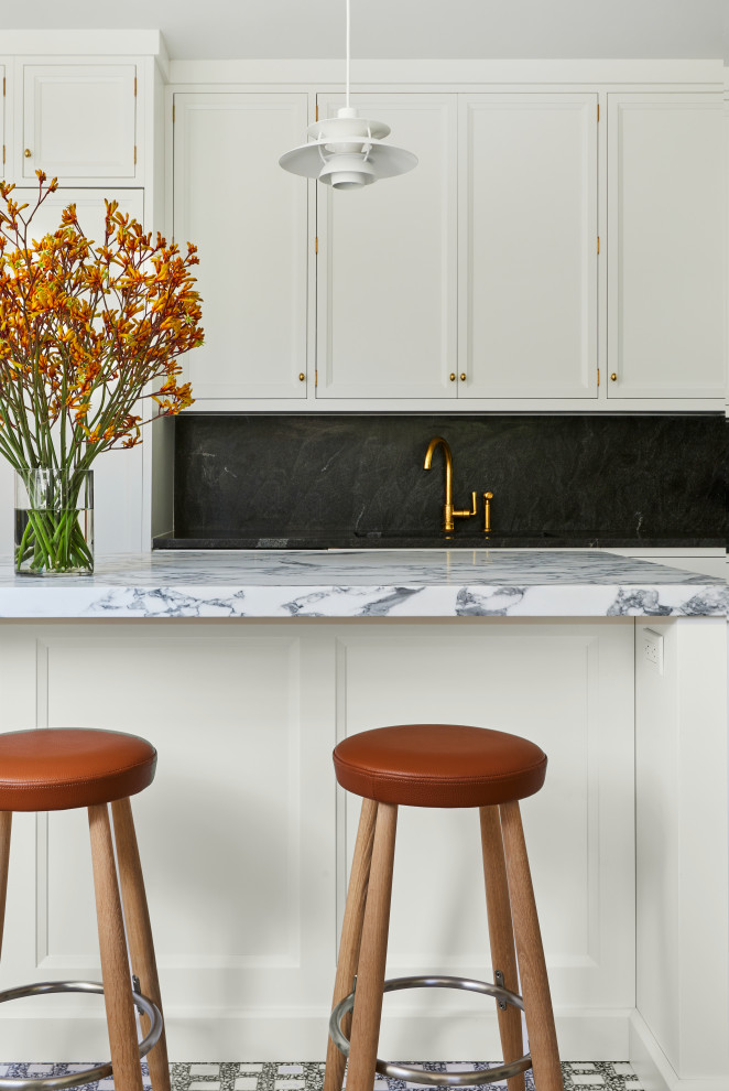 Inredning av ett klassiskt mycket stort grå grått kök, med en undermonterad diskho, luckor med infälld panel, vita skåp, granitbänkskiva, flerfärgad stänkskydd, stänkskydd i sten, integrerade vitvaror, marmorgolv, en köksö och flerfärgat golv