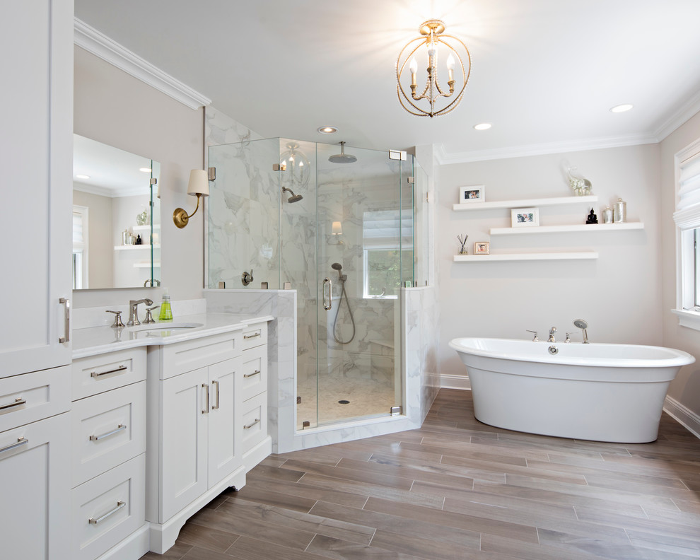 Design ideas for a large transitional master bathroom in New York with shaker cabinets, white cabinets, a freestanding tub, a corner shower, a two-piece toilet, white tile, stone tile, beige walls, ceramic floors, an undermount sink and engineered quartz benchtops.