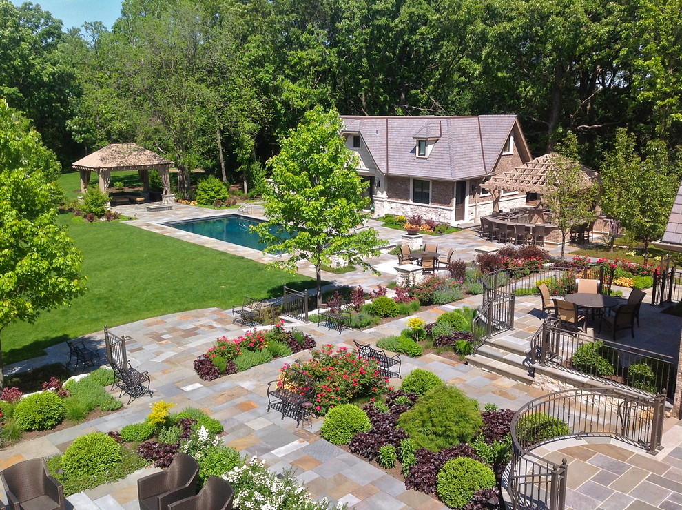 Large traditional backyard full sun formal garden in Chicago with with privacy feature and natural stone pavers for summer.
