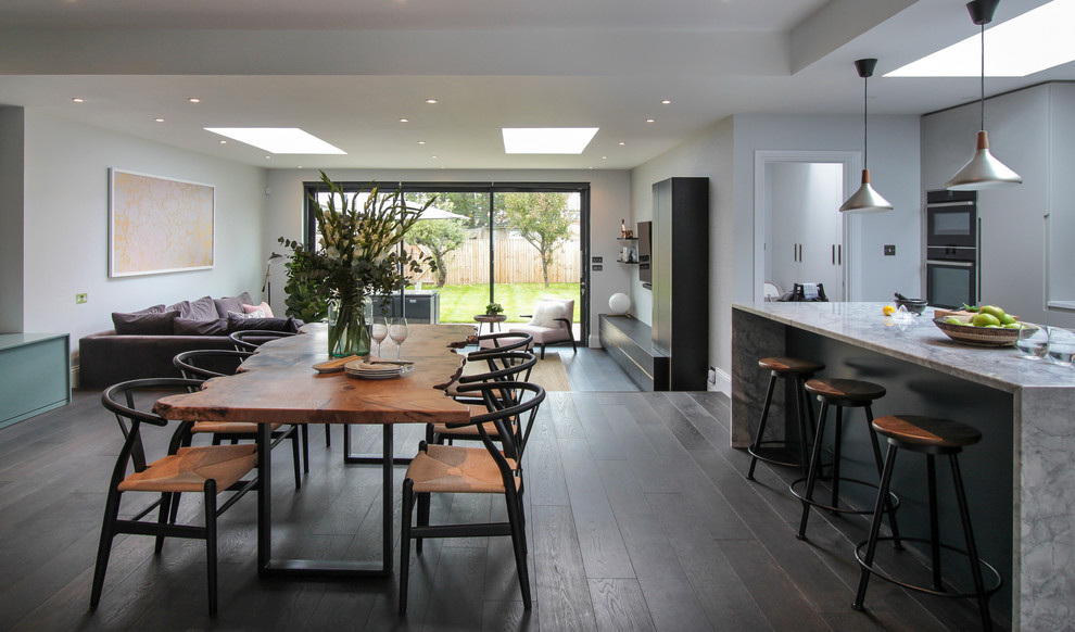 This is an example of a large contemporary open plan dining in London with white walls, dark hardwood floors, no fireplace and brown floor.