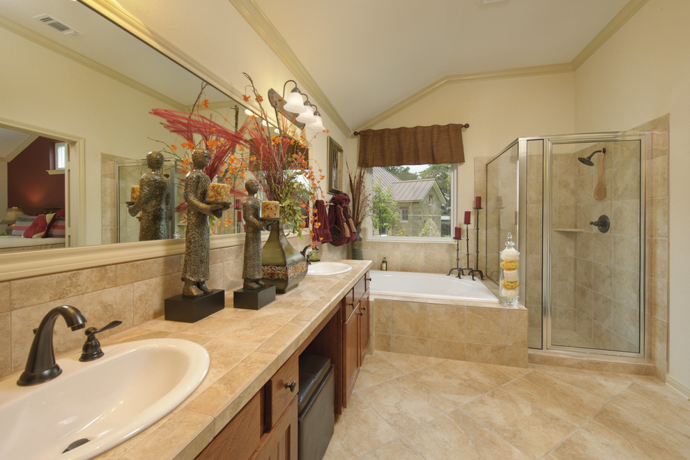 This is an example of a mid-sized transitional master bathroom in Houston with recessed-panel cabinets, medium wood cabinets, a drop-in tub, a corner shower, beige tile, travertine, beige walls, travertine floors, a drop-in sink, terrazzo benchtops, beige floor, a hinged shower door and beige benchtops.