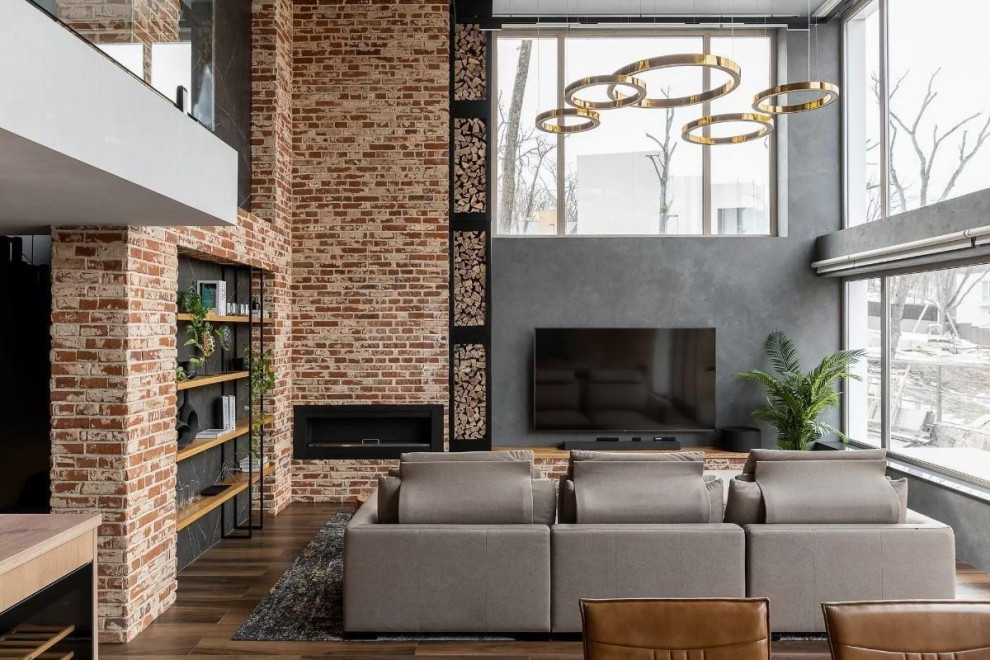 Large contemporary loft-style living room in Other with a library, grey walls, porcelain floors, a ribbon fireplace, a metal fireplace surround, a wall-mounted tv, brown floor and brick walls.