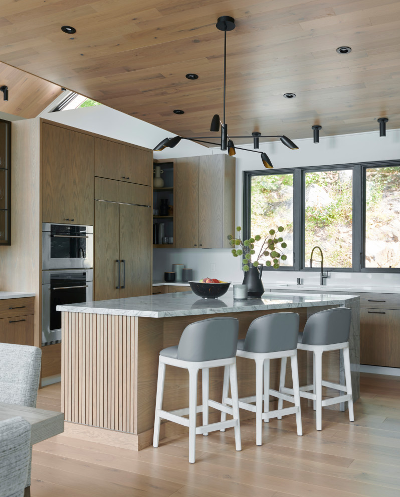 Inspiration for a large contemporary l-shaped open plan kitchen in Toronto with flat-panel cabinets, light wood cabinets, quartz benchtops, white splashback, engineered quartz splashback, with island, white benchtop, an undermount sink, panelled appliances, light hardwood floors and beige floor.