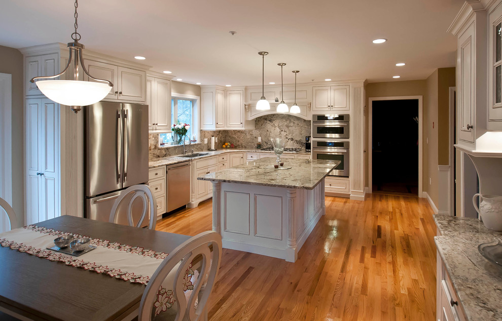 Large traditional u-shaped eat-in kitchen in Boston with an undermount sink, shaker cabinets, white cabinets, medium hardwood floors, with island, brown floor, marble benchtops, multi-coloured splashback, marble splashback and stainless steel appliances.
