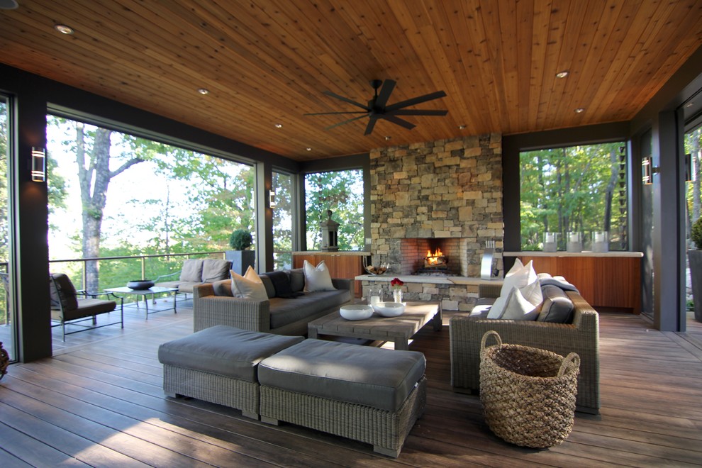 Photo of a large contemporary backyard deck in Raleigh with a fire feature and a roof extension.