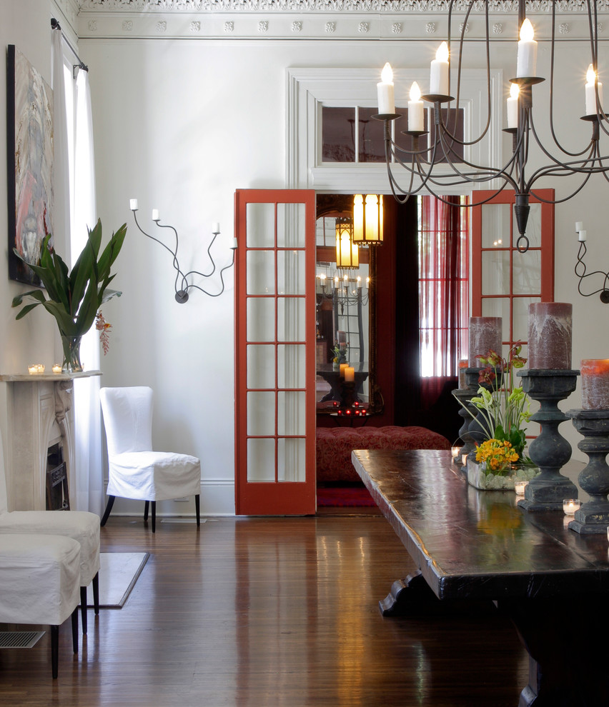 This is an example of a contemporary dining room in New Orleans with white walls and dark hardwood floors.