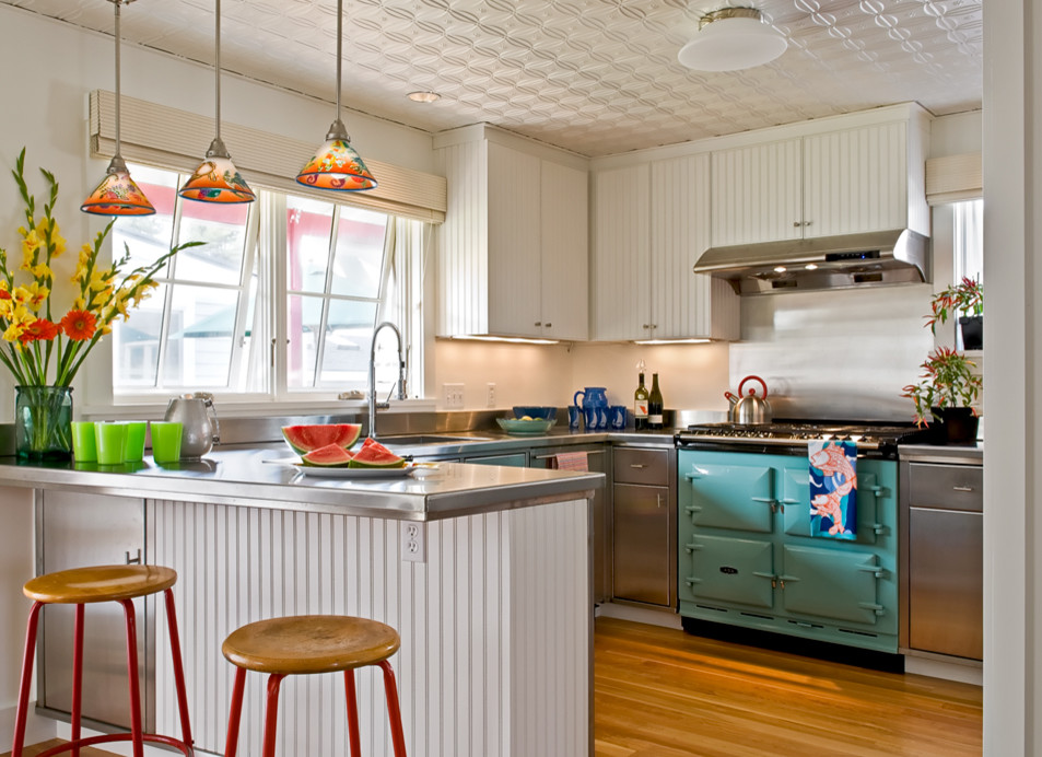 This is an example of a beach style kitchen in Portland Maine with stainless steel cabinets, stainless steel benchtops and coloured appliances.