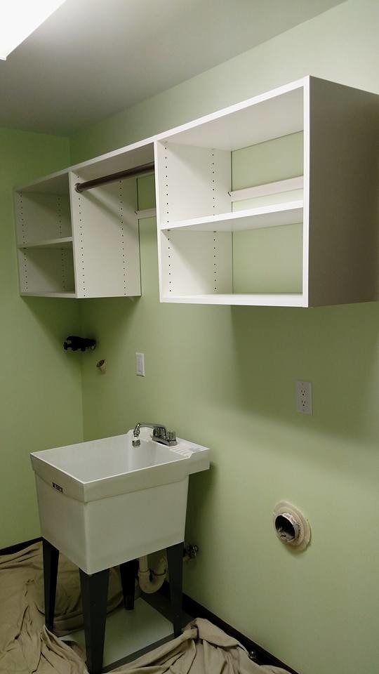 Inspiration for a mid-sized modern single-wall dedicated laundry room in Other with an utility sink, flat-panel cabinets, white cabinets, green walls and a side-by-side washer and dryer.