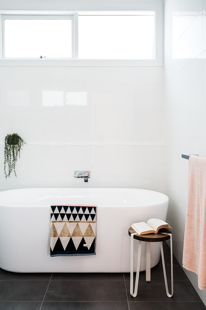 Photo of a mid-sized contemporary 3/4 bathroom in Melbourne with a freestanding tub, white tile, porcelain tile, white walls, ceramic floors and black floor.