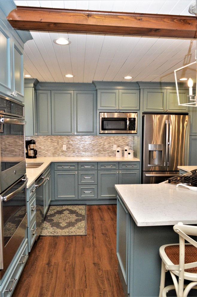 This is an example of a mid-sized transitional l-shaped eat-in kitchen in Other with an undermount sink, recessed-panel cabinets, blue cabinets, quartzite benchtops, multi-coloured splashback, stainless steel appliances, medium hardwood floors, with island, brown floor and white benchtop.