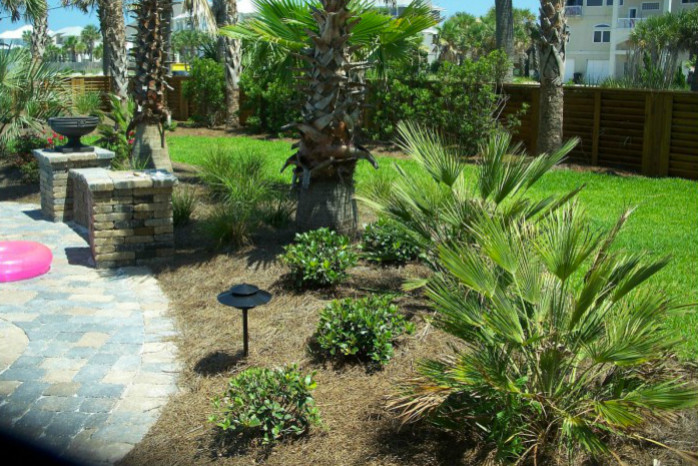 Inspiration for a mid-sized contemporary backyard partial sun garden in Miami with a retaining wall and natural stone pavers.