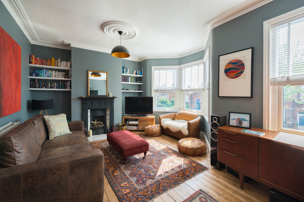 Photo of a mid-sized victorian family room in London with grey walls, a standard fireplace, a freestanding tv, a library, a tile fireplace surround and medium hardwood floors.