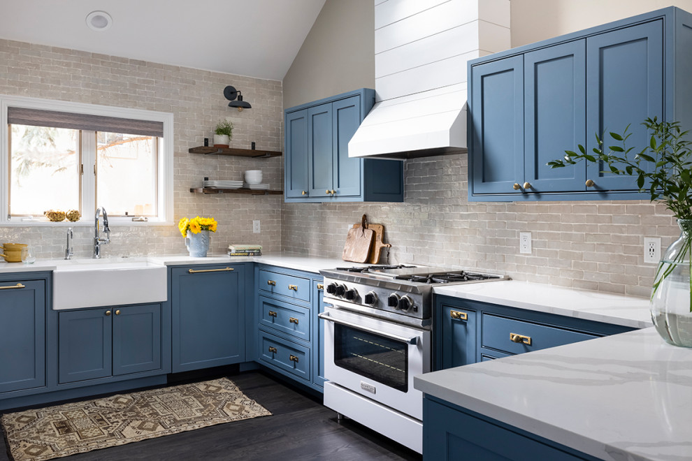 Design ideas for a medium sized farmhouse u-shaped kitchen in Denver with a belfast sink, shaker cabinets, blue cabinets, engineered stone countertops, white splashback, metro tiled splashback, integrated appliances, dark hardwood flooring, brown floors, white worktops and a vaulted ceiling.