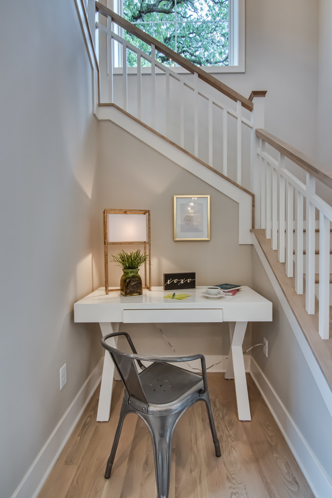 Small beach style home office in Minneapolis with light hardwood floors, no fireplace and a freestanding desk.
