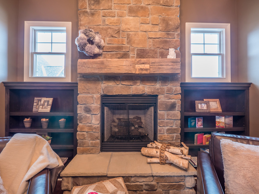 Inspiration for a country study room in Indianapolis with brown walls, dark hardwood floors, a standard fireplace, a stone fireplace surround and a freestanding desk.