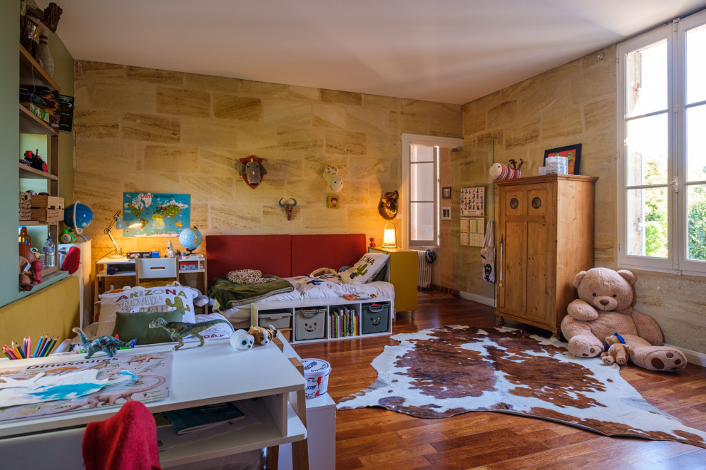 Klassisk inredning av ett stort pojkrum kombinerat med sovrum och för 4-10-åringar, med flerfärgade väggar, mörkt trägolv och rött golv