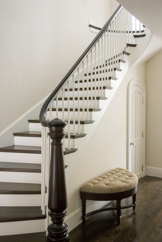 This is an example of a large traditional wood curved staircase in Boston with painted wood risers.