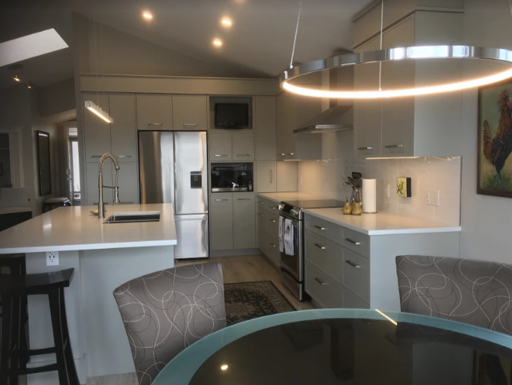 Eat-in kitchen - mid-sized transitional u-shaped light wood floor and beige floor eat-in kitchen idea in Calgary with an undermount sink, recessed-panel cabinets, gray cabinets, quartzite countertops, white backsplash, stone slab backsplash, stainless steel appliances, an island and white countertops