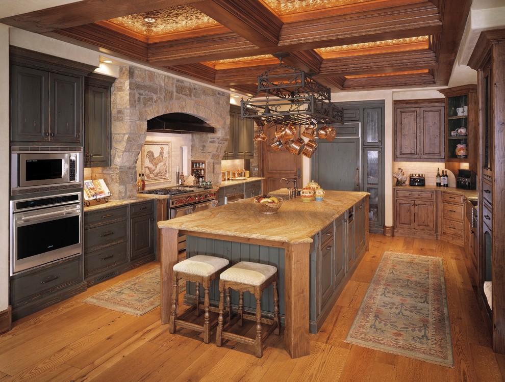 Inspiration for a large country u-shaped medium tone wood floor eat-in kitchen remodel in Denver with a farmhouse sink, raised-panel cabinets, distressed cabinets, granite countertops, multicolored backsplash, paneled appliances and an island