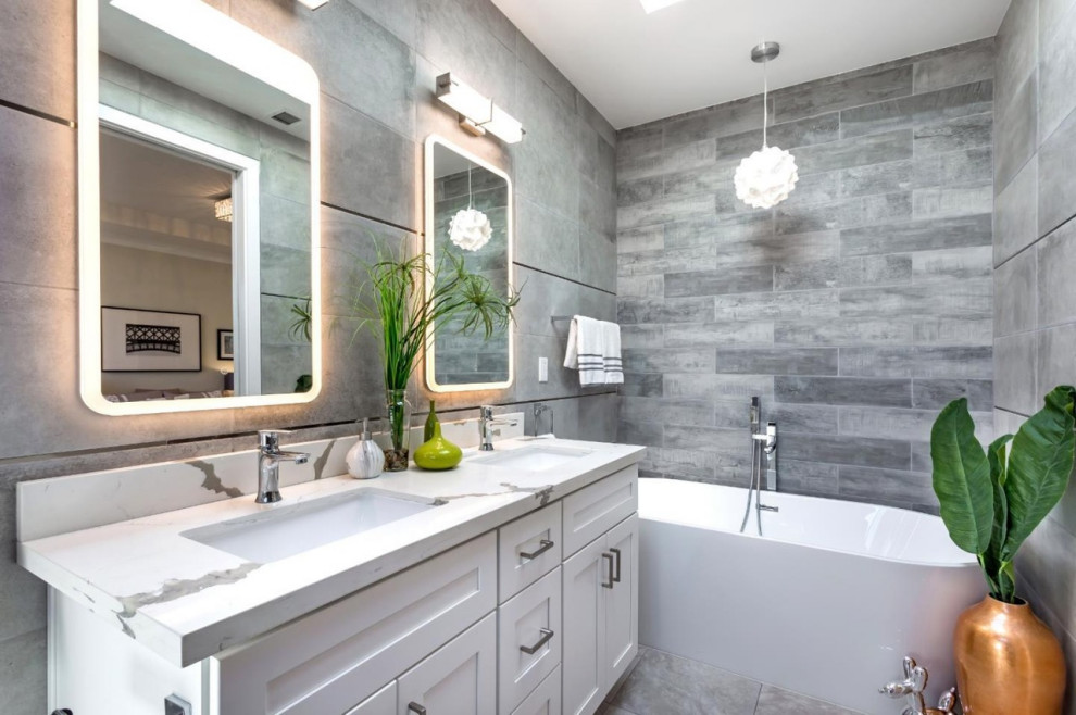 Photo of a mid-sized mediterranean master bathroom in San Francisco with shaker cabinets, white cabinets, a freestanding tub, an alcove shower, a one-piece toilet, gray tile, porcelain tile, grey walls, porcelain floors, a drop-in sink, engineered quartz benchtops, grey floor, a hinged shower door, white benchtops, a shower seat, a double vanity and a built-in vanity.